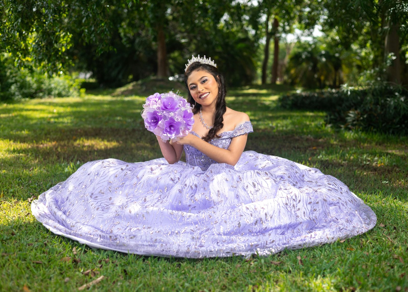 A vibrant portrait of a young woman in a lavender quinceañera dress, outdoors with a bouquet.
