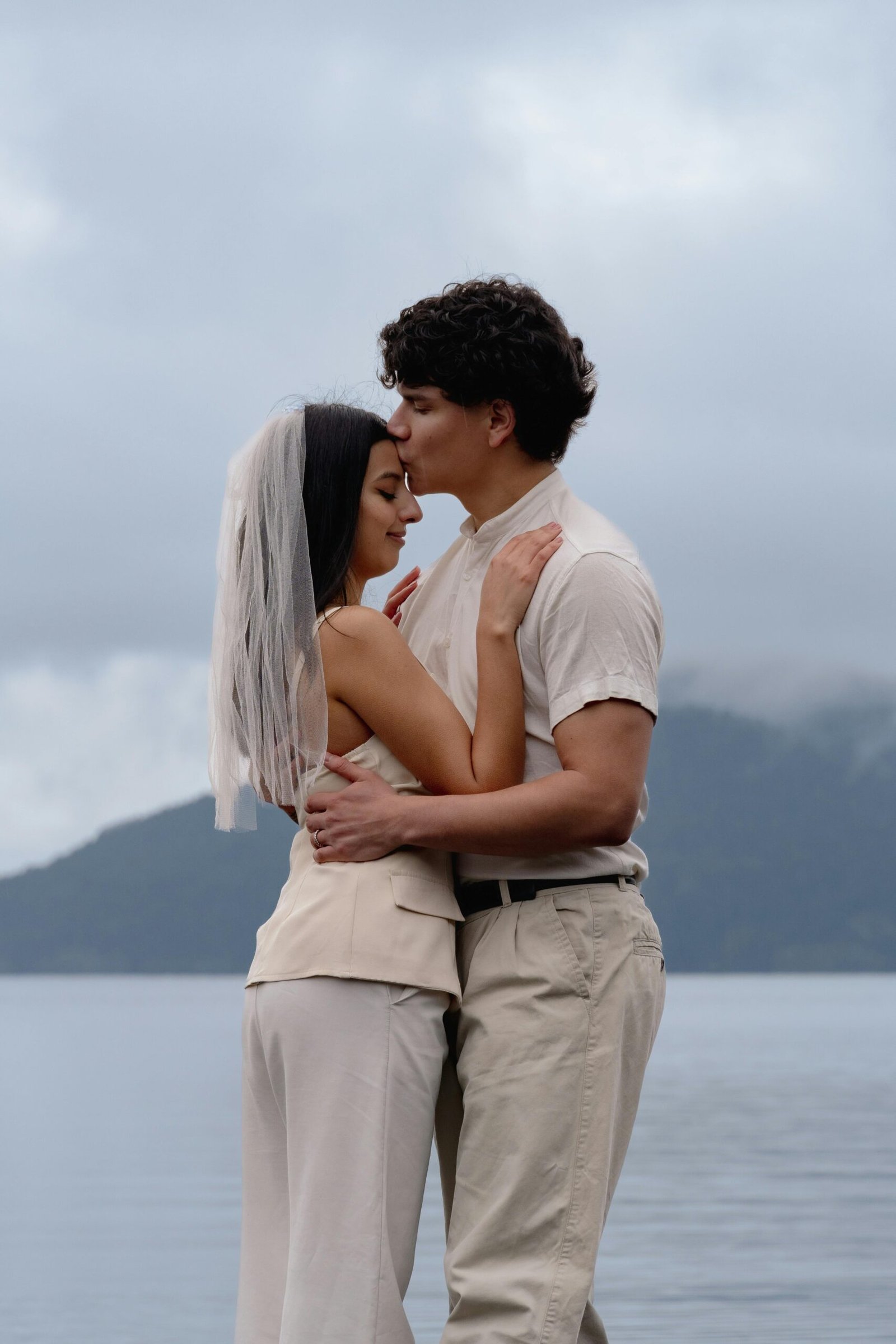 Newlywed couple embracing by a serene lake in Bariloche, capturing love and tranquility.
